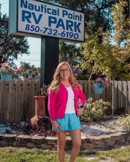 female owner of rv park standing at entrance in front of nautical point rv park sign