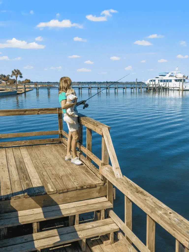 woman and her dog fishing off pier that can launch paddleboards, kayaks, canoes